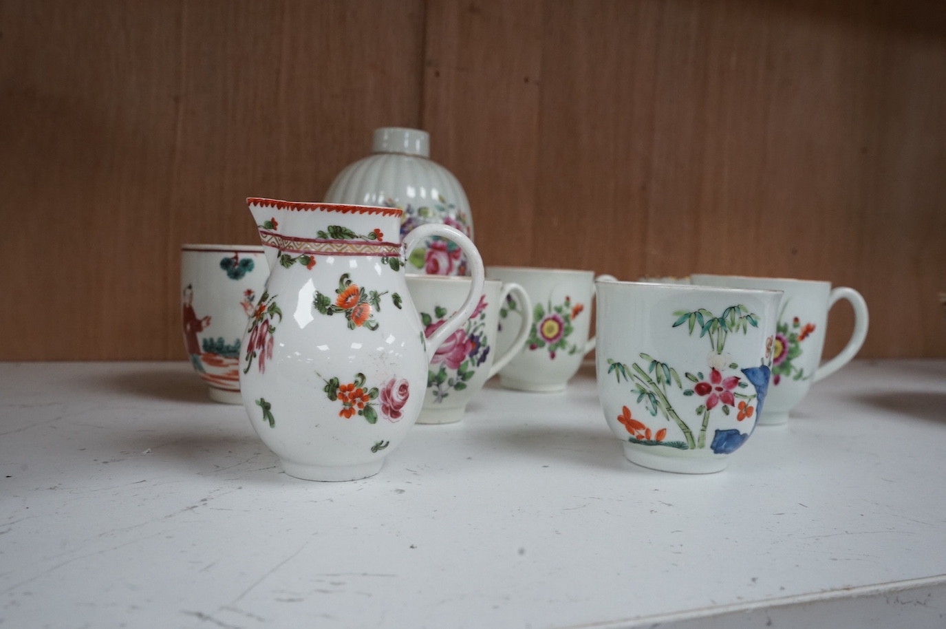 Worcester polychrome tea and coffee wares, c.1760-1780, comprising a tea caddy, a cream jug, five coffee cups and a fluted bowl, the latter with red anchor mark (8), largest tea caddy 14cm high.